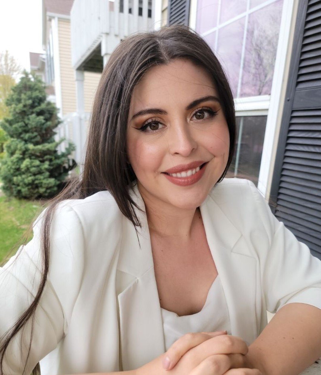 Smiling person sitting outdoors near house.