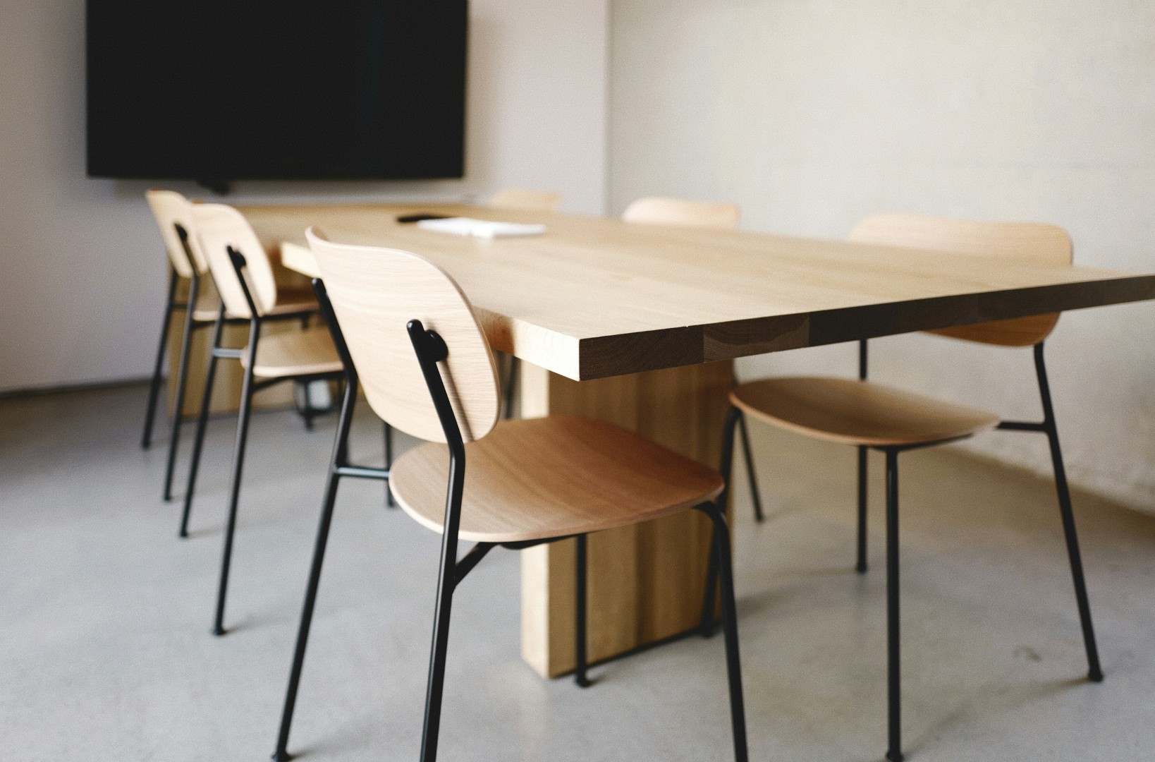 Wooden conference table with chairs in modern room.