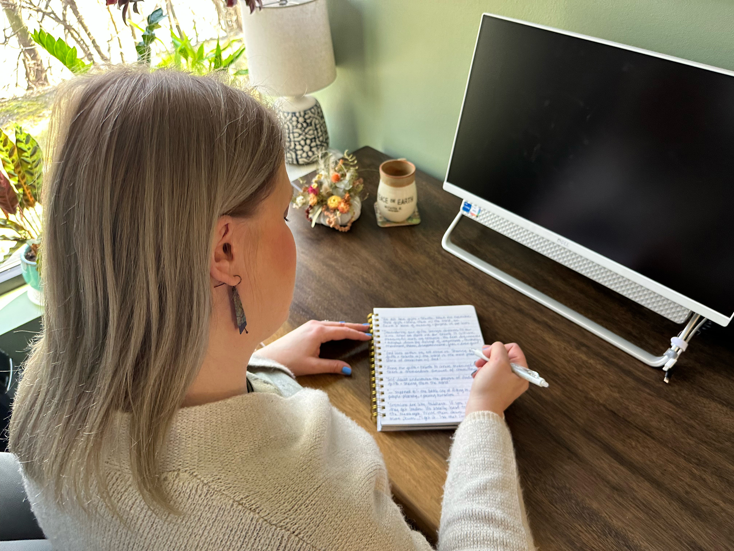 Woman writing notes at desk with notebook