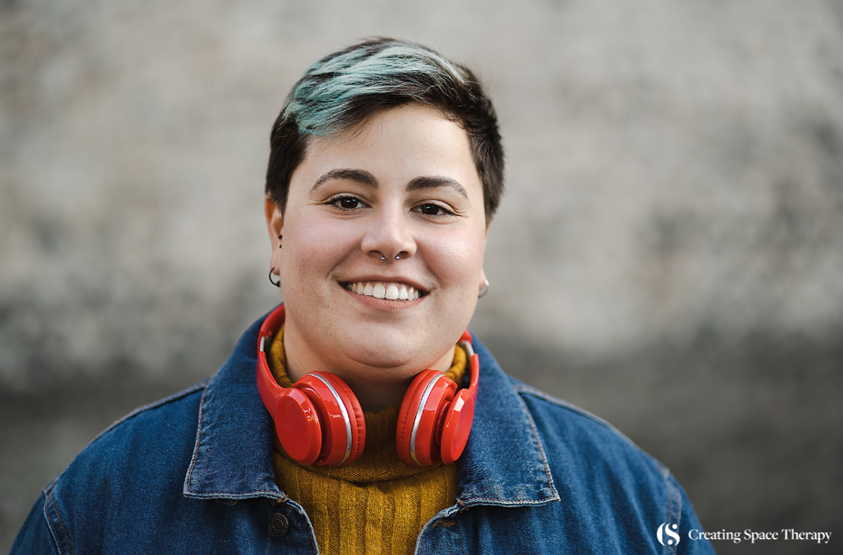 Plus-size lesbian wearing headphones, enjoying music outdoors with a relaxed and content expression.
