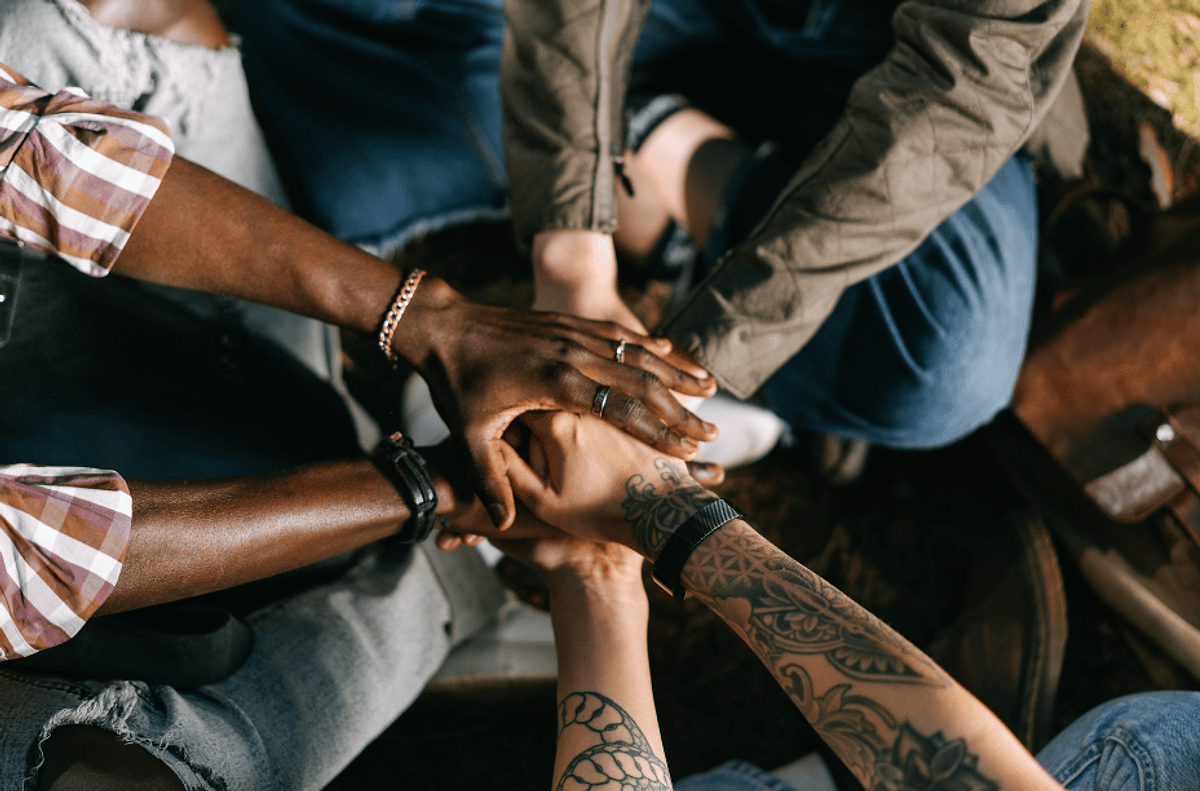 Hands of diverse individuals stacked together in unity, symbolizing support, resilience, and connection during uncertain anxious times.