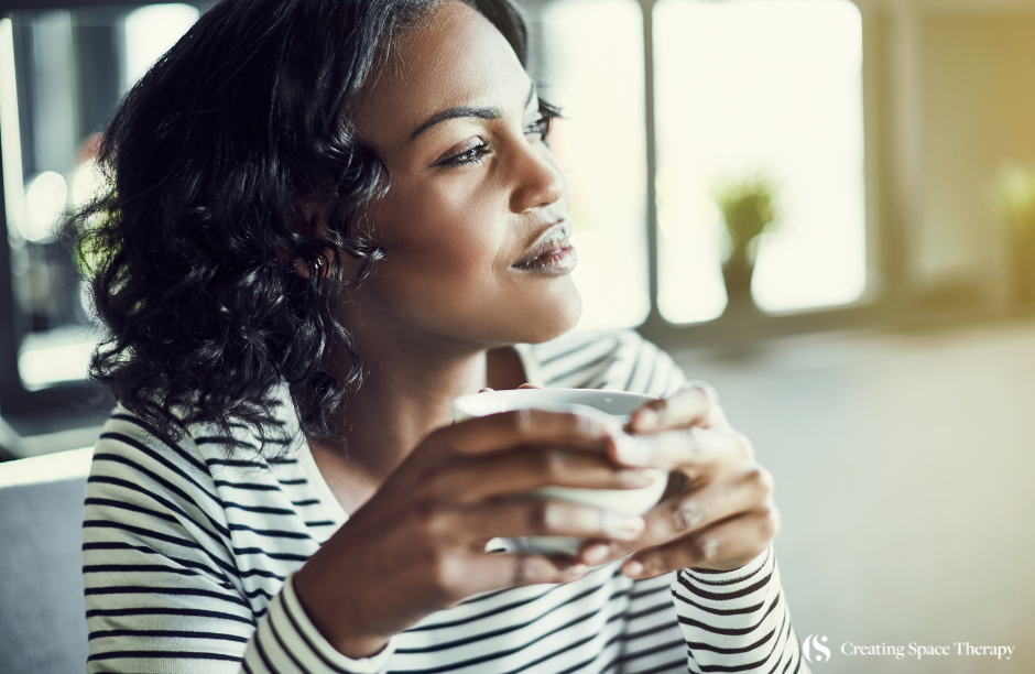 Woman enjoying coffee, looking thoughtful and relaxed.