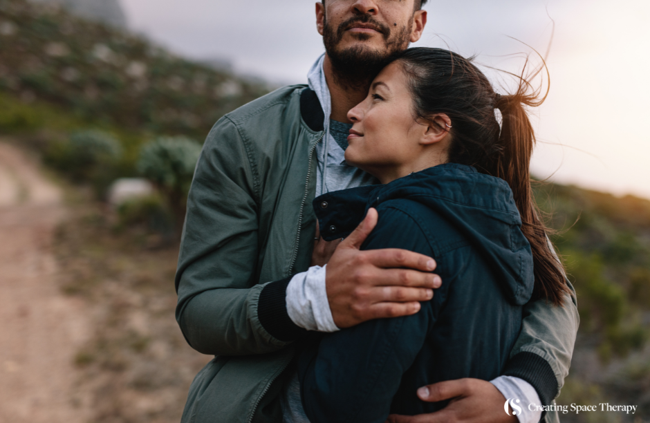 Couple embracing outdoors in nature setting.