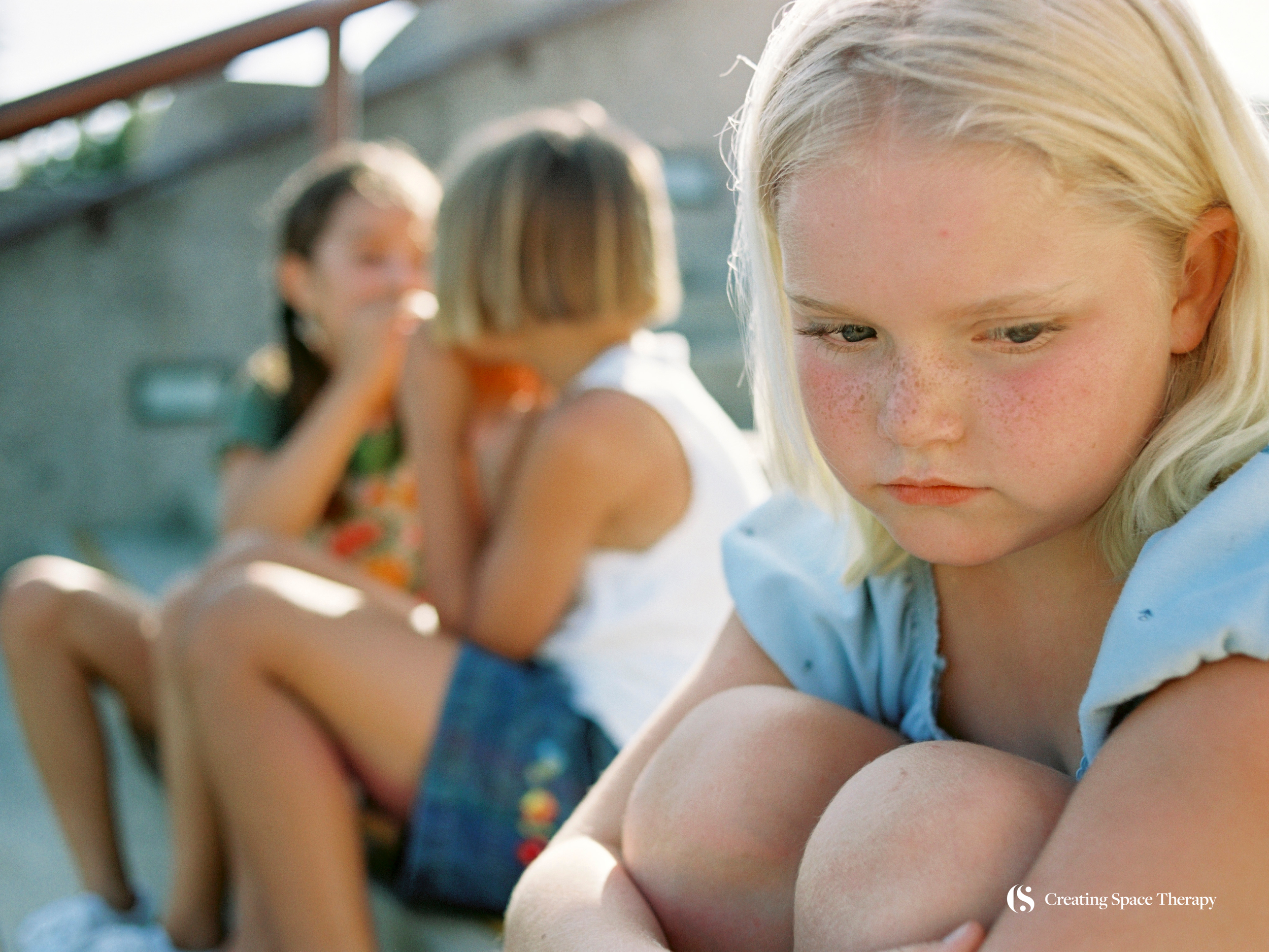 Sad child sitting alone on steps.