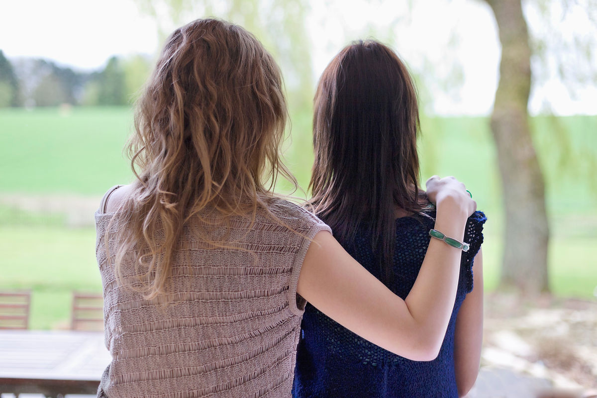 Two women standing together, one with their arm around the other in a comforting gesture, symbolizing support and healing from emotional trauma.