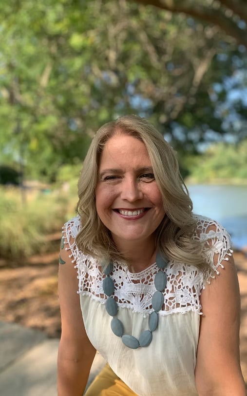 Women smiling outdoors near a tree.
