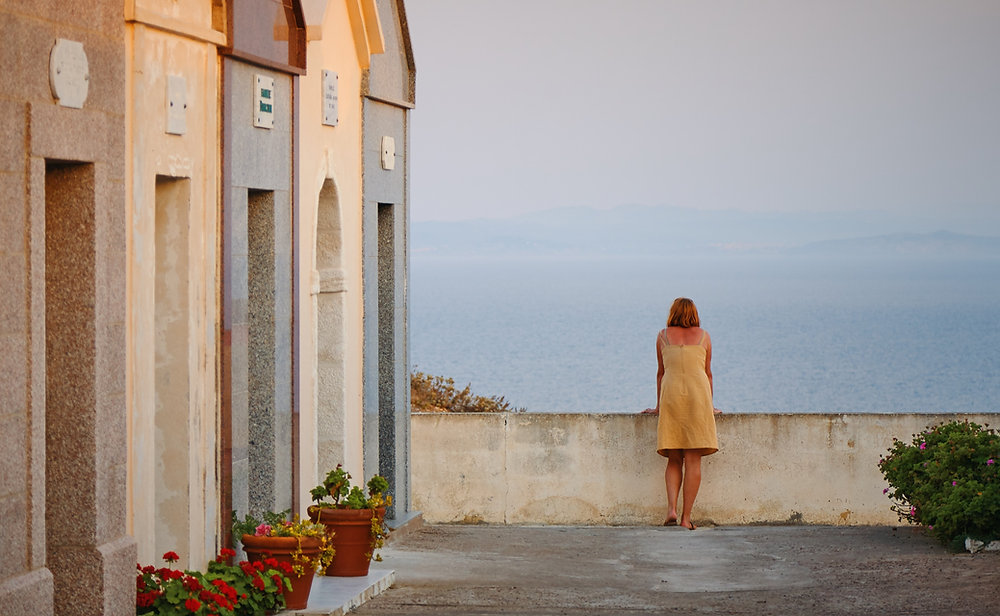 Woman in yellow dress overlooks ocean view.