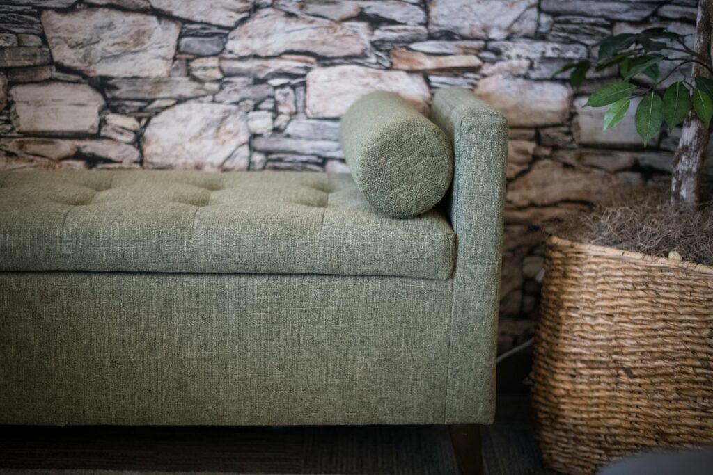 Green upholstered bench beside woven plant basket