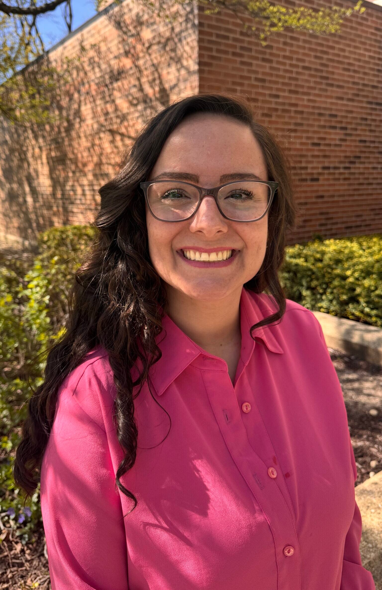 Paula Rainey in a pink shirt standing outside in the spring